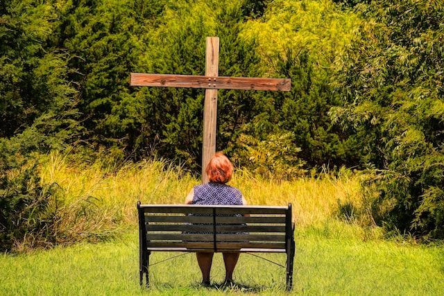 lady sitting in outdoors in front of cross